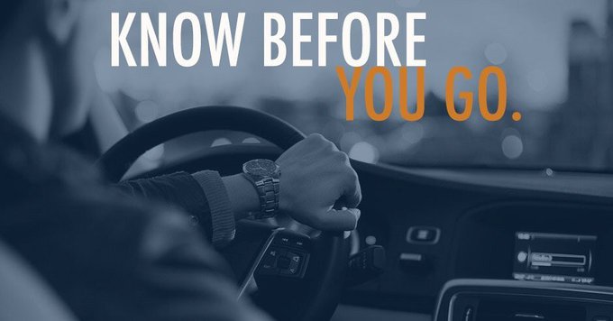 Photo featuring a man's hand driving wearing a nice watch with a navy blue overlay and the wording "Know Before You Go" displayed in white and blue lettering.