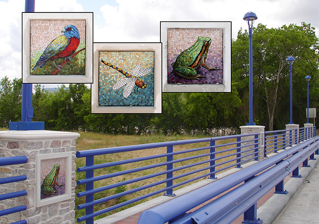 Benmar Bridge Decorative bridge with blue railings featuring inset mosaic artwork panels of a bird, dragonfly, and frog along a landscaped pedestrian pathway.
