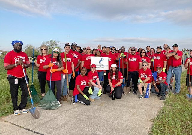 GBC Tree Planting 11 Large group of volunteers in red shirts pose with planting tools and a Greens Bayou Coalition sign during a community tree planting event.