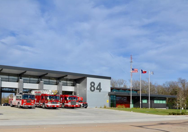 HFD Station 84 Houston Fire Department Station 84 building with multiple fire trucks parked outside the modern fire station facility.