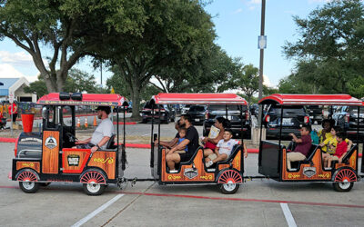 National Night Out 2025 8 Families and children ride a small trackless train with multiple open cars along a paved area, enjoying an activity at an outdoor community event.