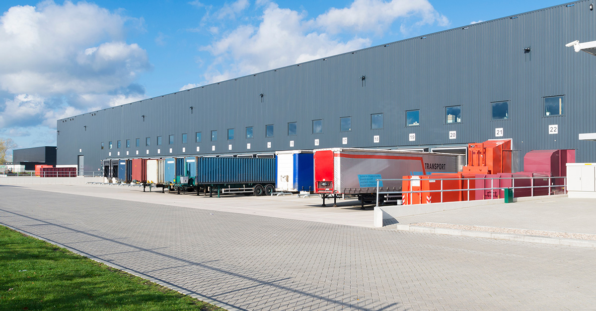 A large industrial warehouse with multiple loading docks is shown with semi-trailers backed into bays, representing new industrial development within the North Houston District.