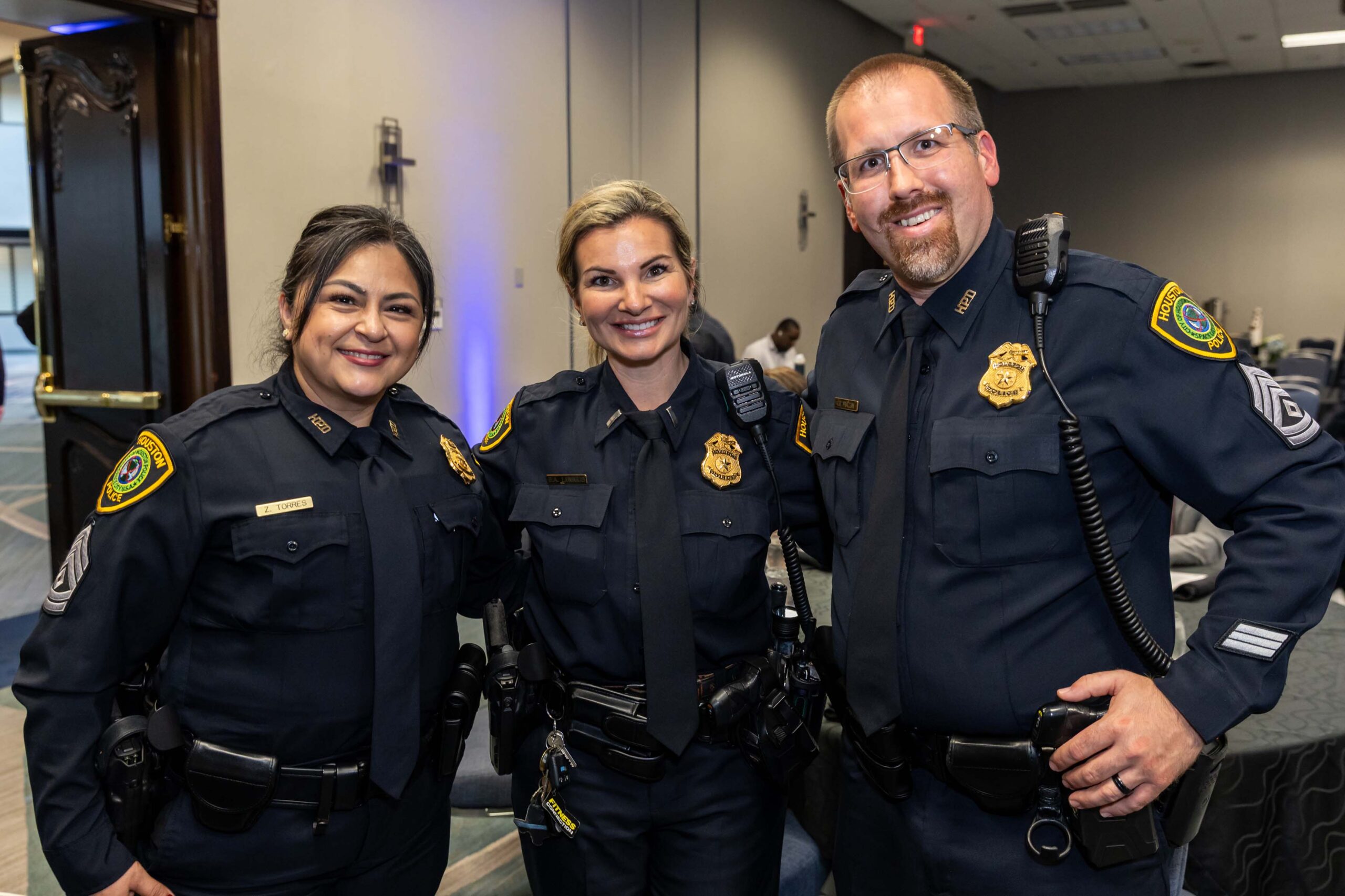 Three HPD officers pose side by side indoors at the awards luncheon.