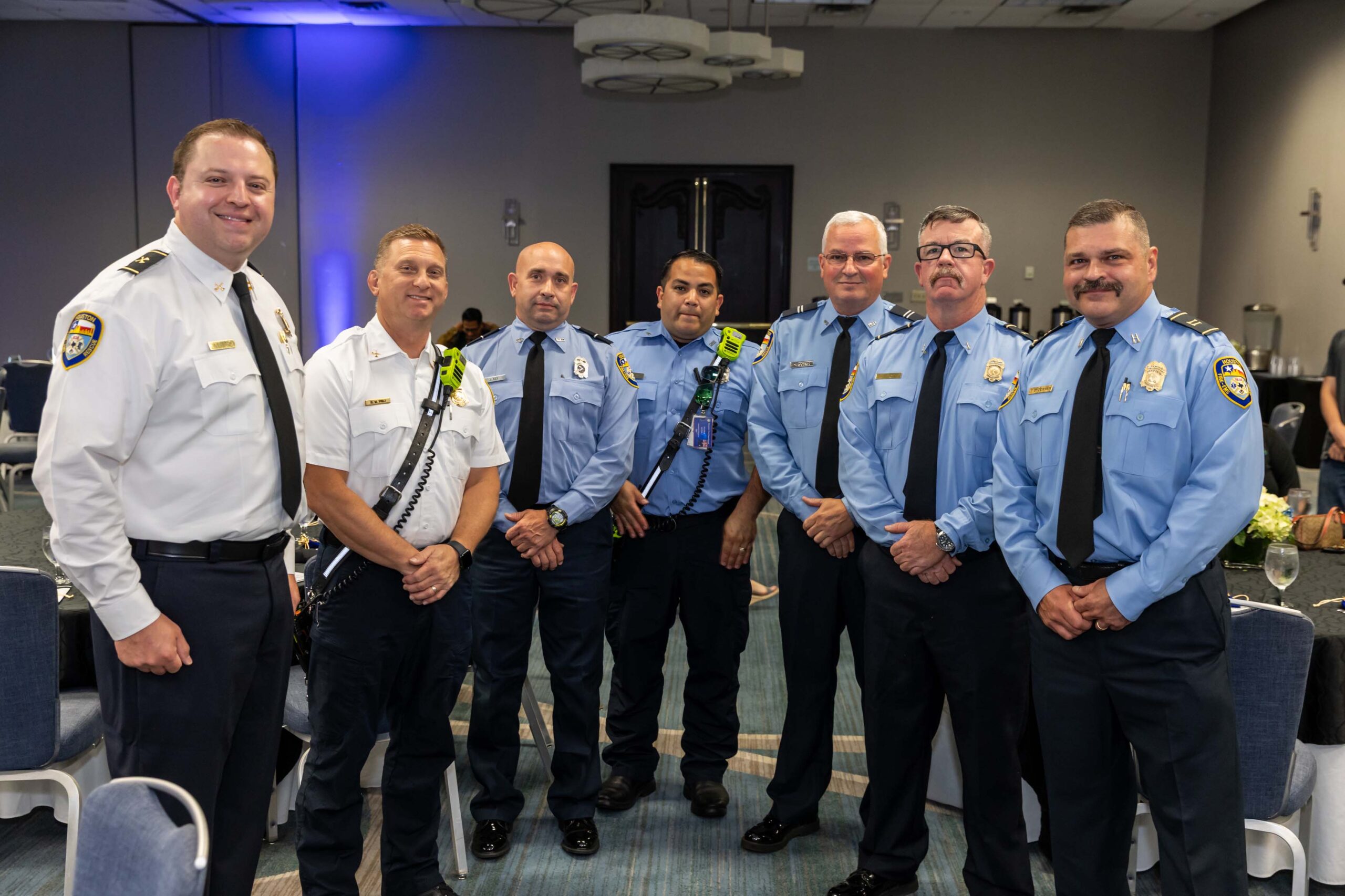 Seven Houston Fire Department staff pose together in matching blue uniforms.