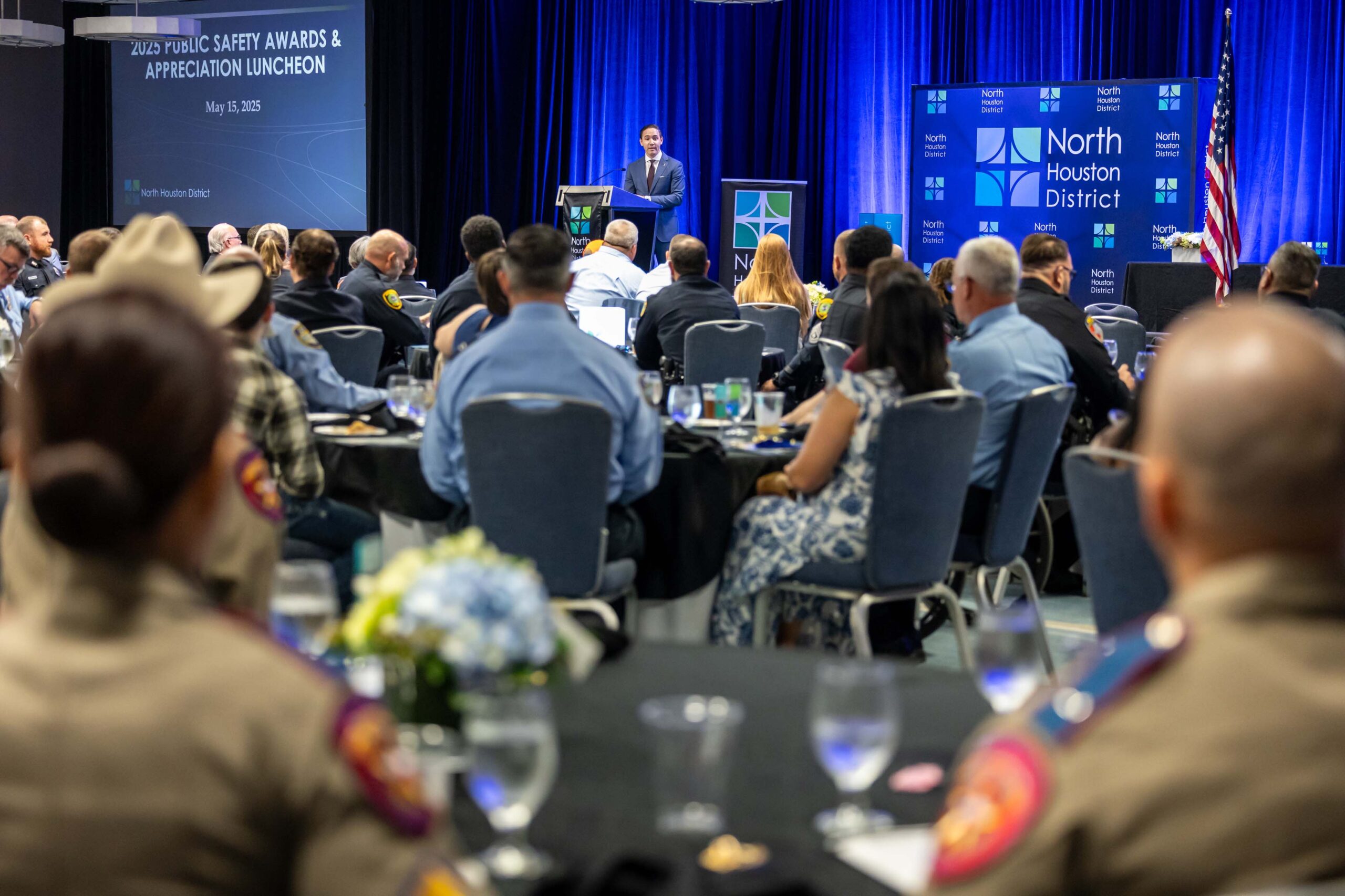 A wide view of the room shows an audience listening to a speaker at the podium during the awards program.