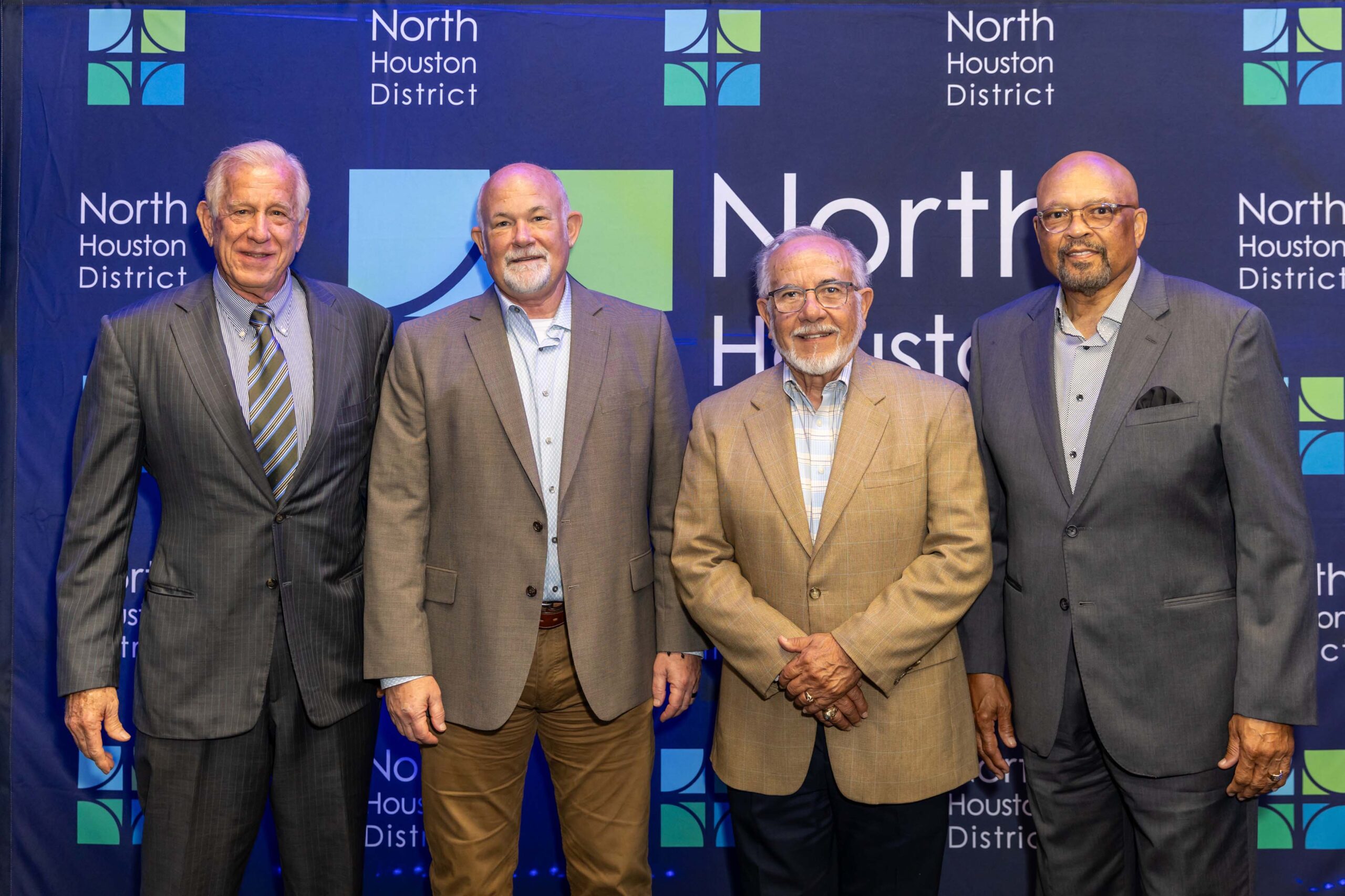 Four men pose together at the 2025 Public Safety Awards Luncheon in business attire, smiling in front of a wall featuring the North Houston District logo.