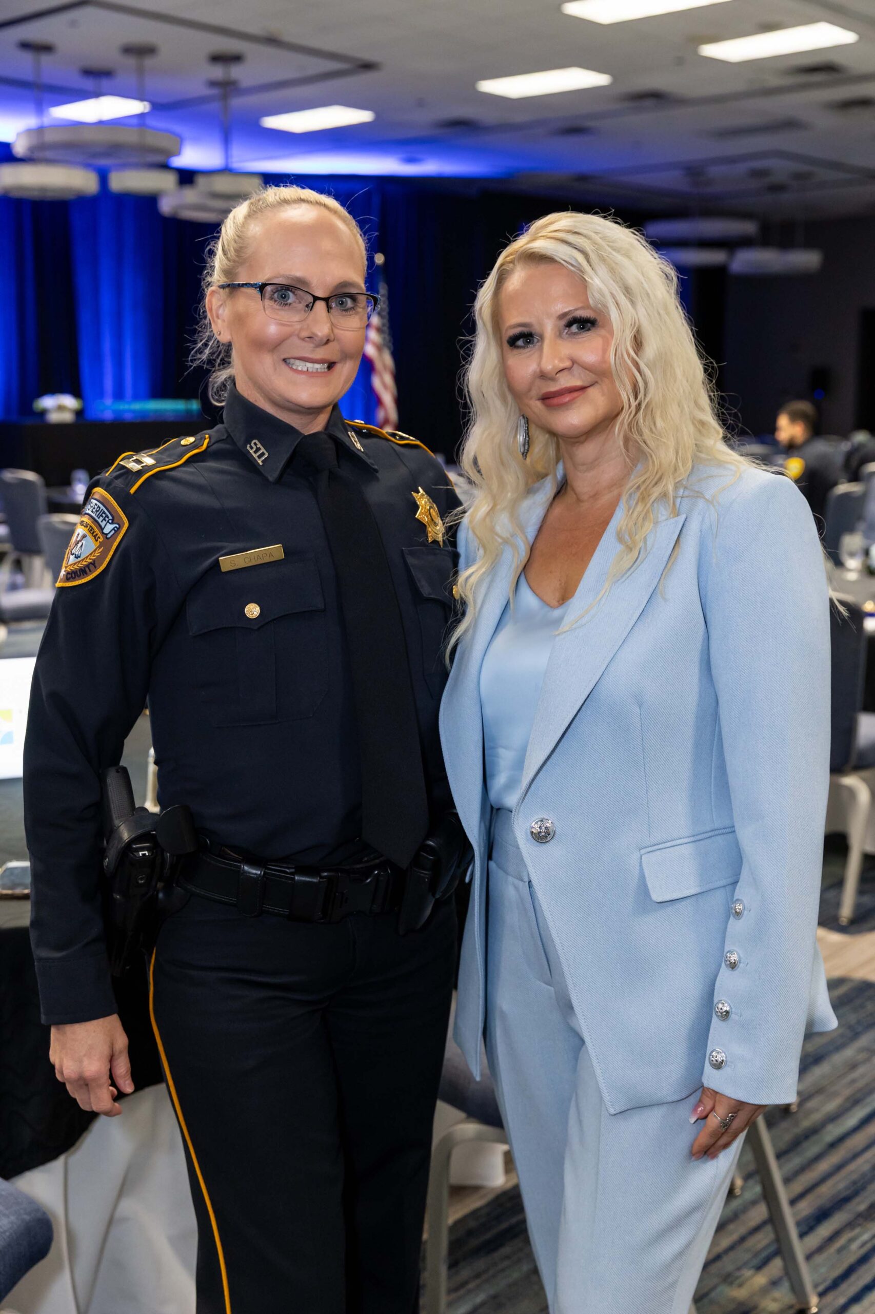 A uniformed deputy poses for a photo with a woman in a light blue suit.