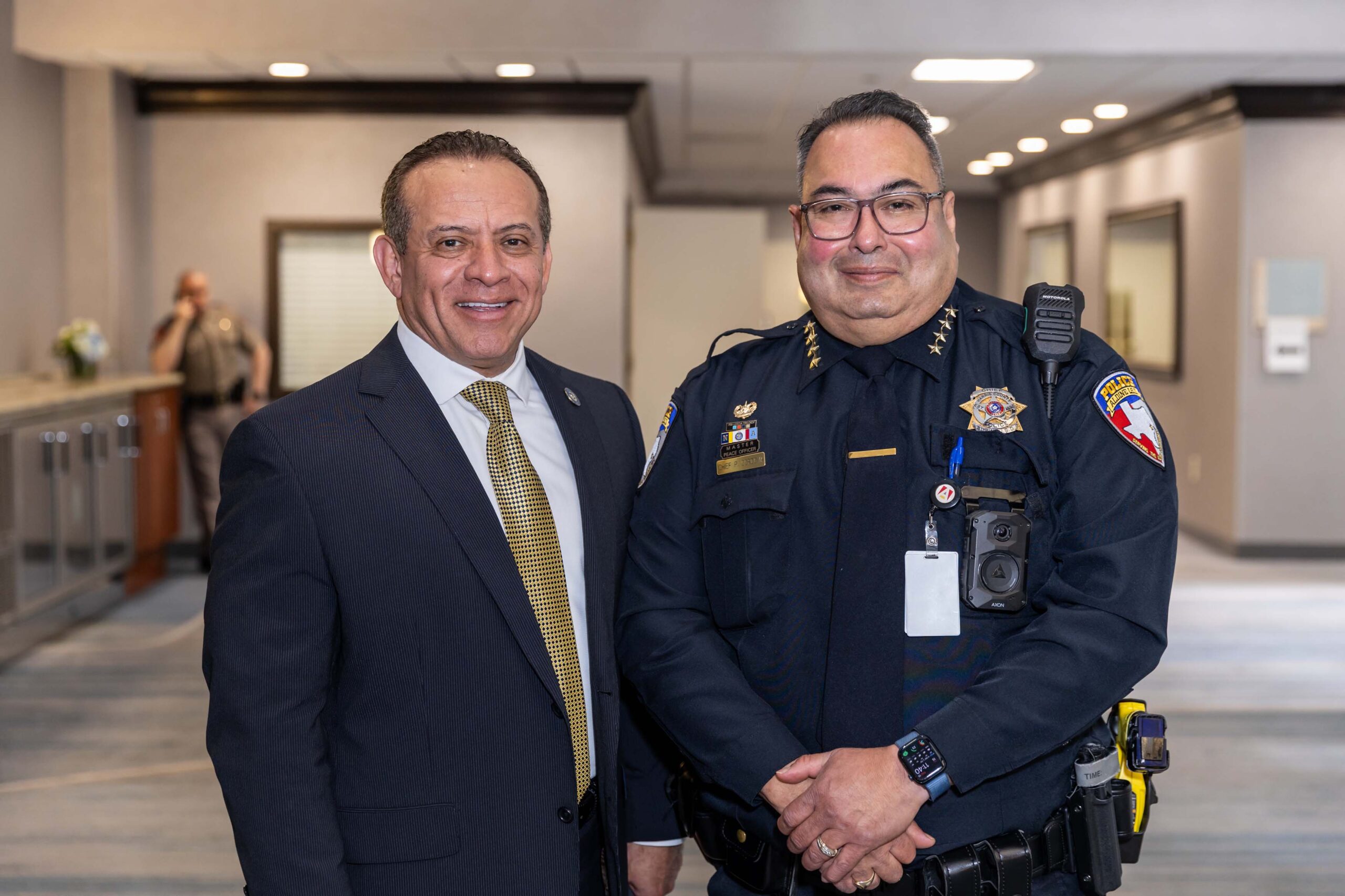 Two men, one in a dark suit and one in police uniform, pose together.