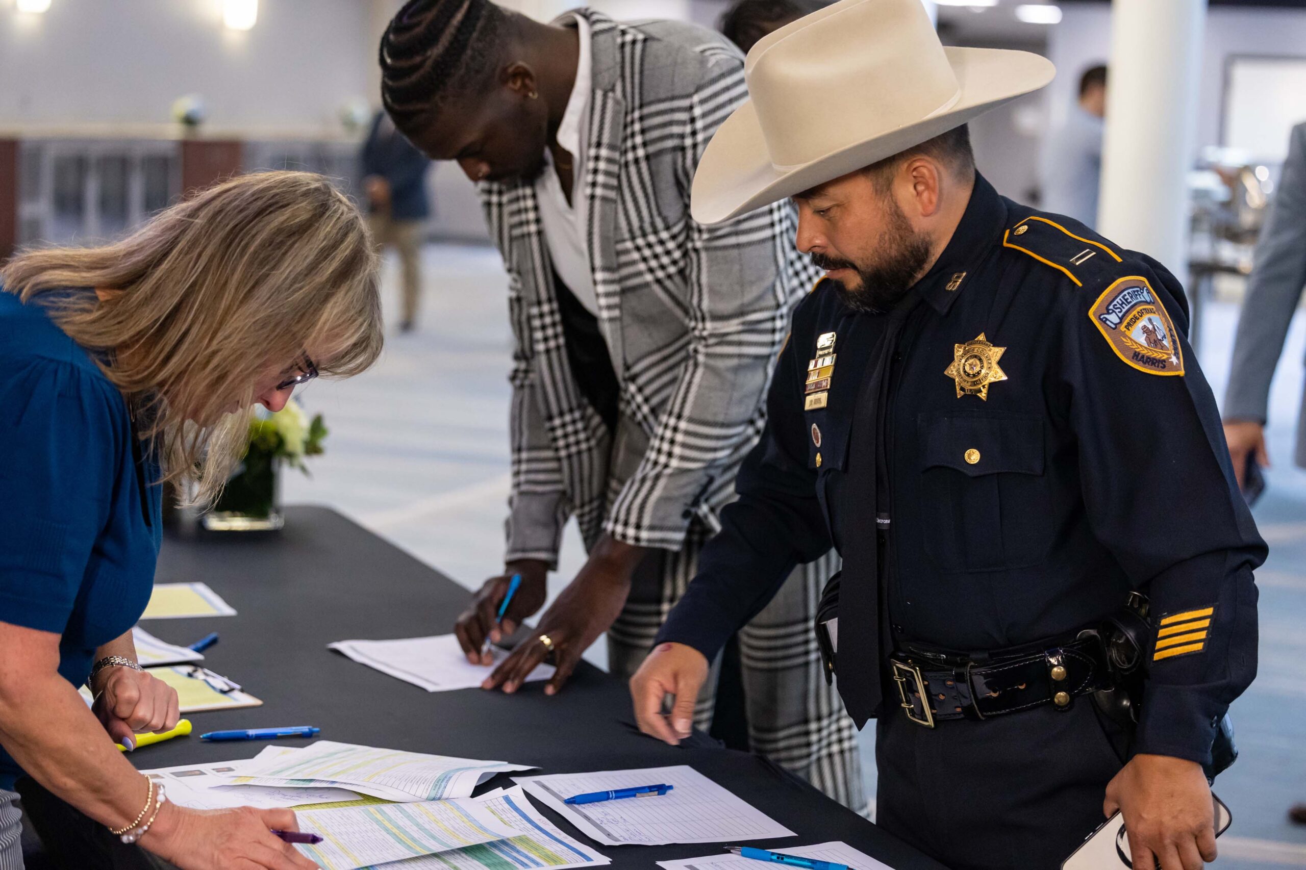 A sheriff's deputy in a cowboy hat signs in at the registration table.