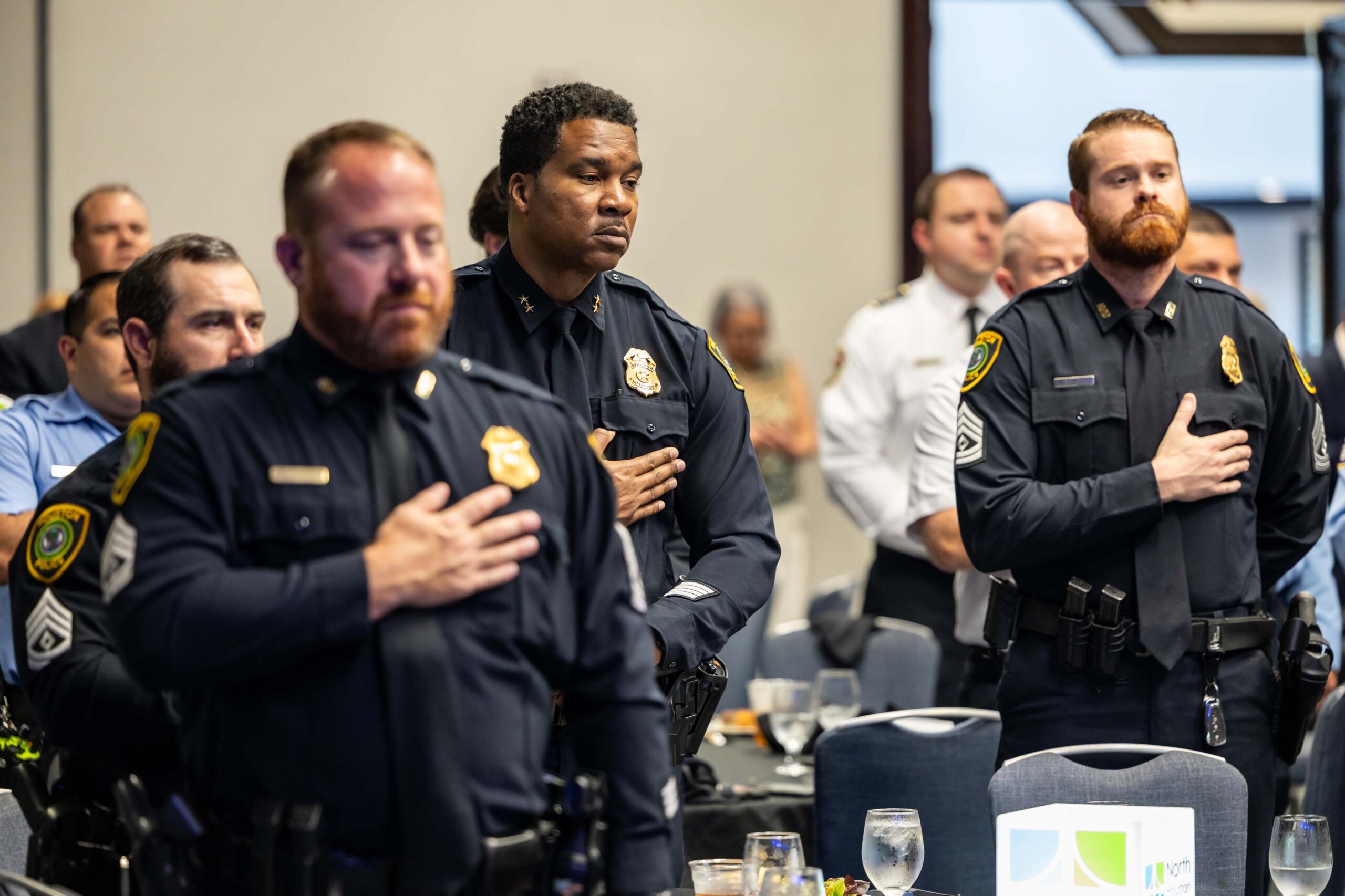 Uniformed officers stand during the National Anthem with hands over hearts.