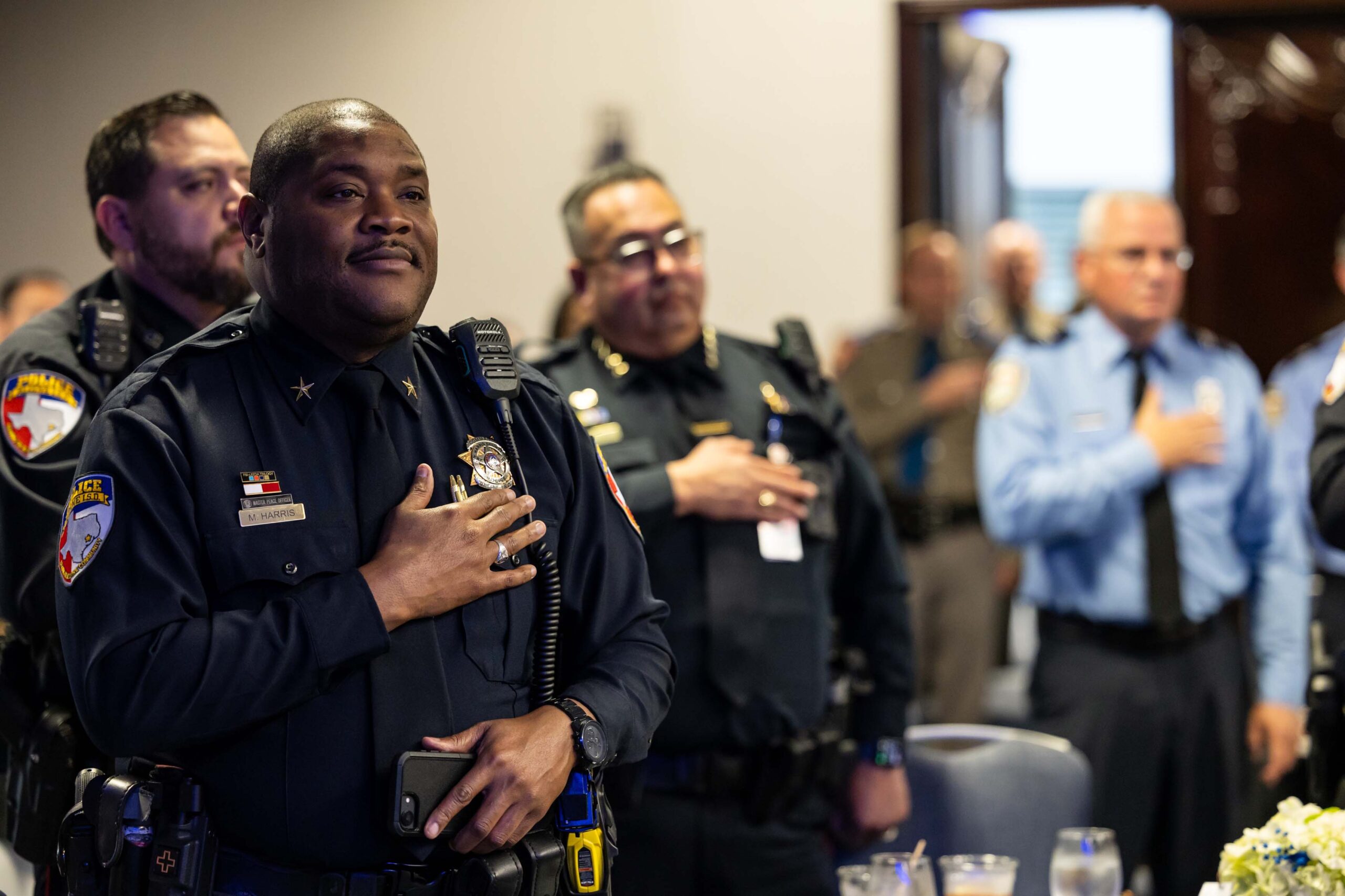Officers and guests stand with hands over hearts during the opening ceremony.