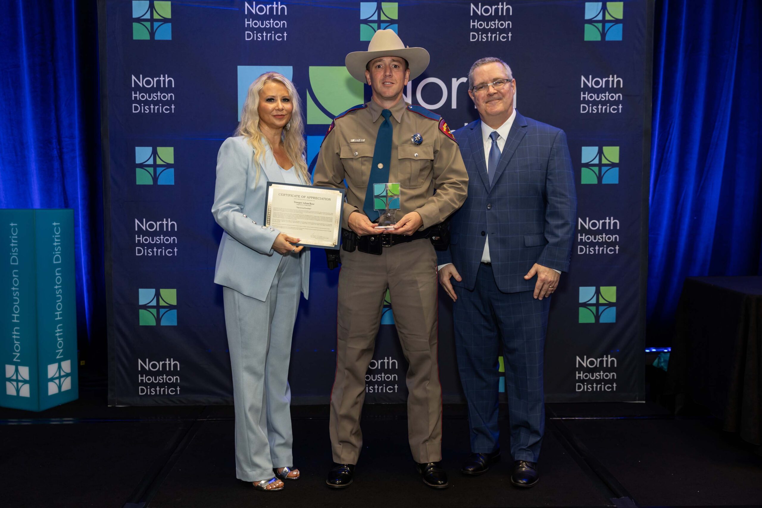 A Texas DPS Trooper poses with two North Houston District leaders, holding his award and certificate.