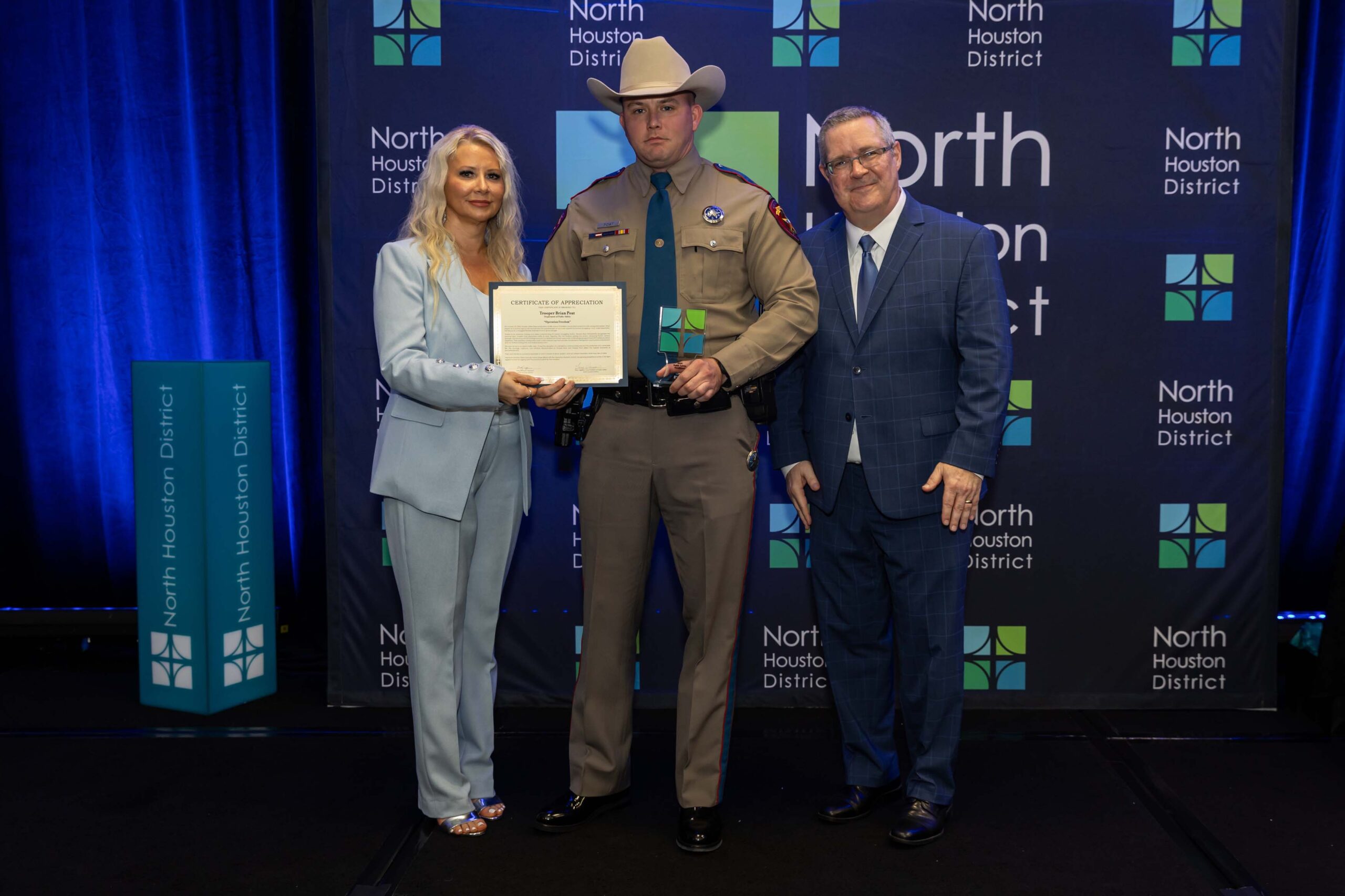 Another DPS Trooper poses with North Houston District representatives, holding a plaque and certificate.