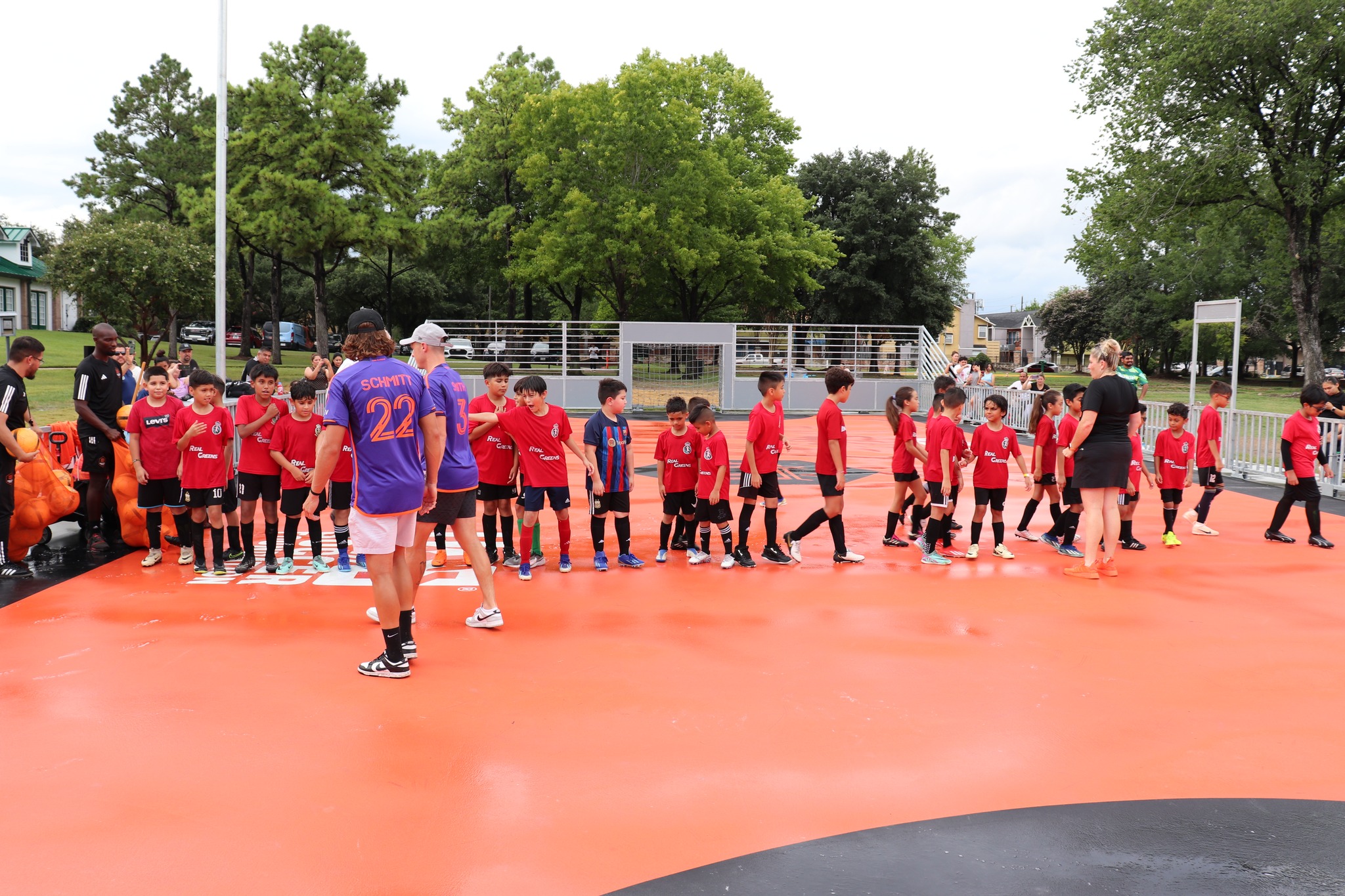 Real Greens Soccer Club kids in red uniforms standing on an orange surface